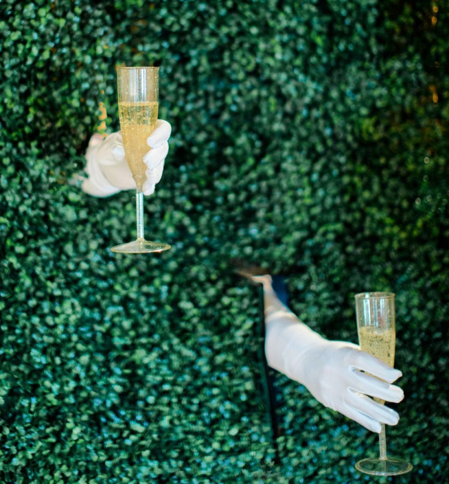 Servers wearing white gloves coming through living champagne wall to serve champagne after the bell was rung
